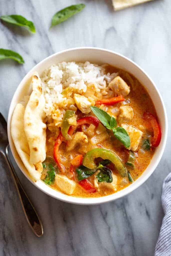 Panang Curry in a bowl with white rice and naan bread.