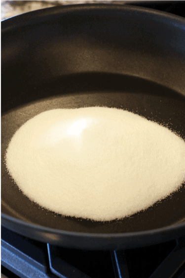Granulated sugar in a skillet on the stove. 