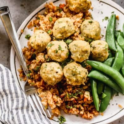 Homemade Baked Chicken Meatballs served on a plate on top of wild rice pilaf and cooked green beans.