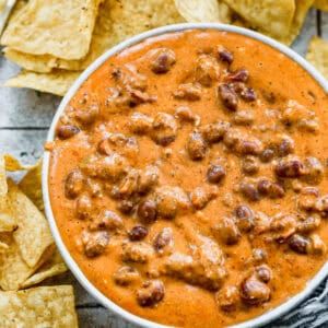 An easy Chili Cheese Dip made with just four ingredients served in a white bowl with tortilla chips.