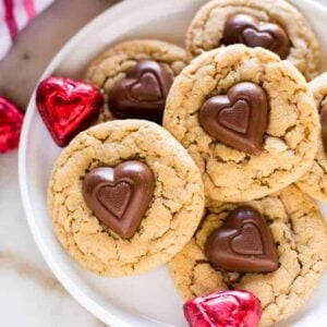 Peanut Butter Cookies with a reese's chocolate heart in the center, stacked on a plate.