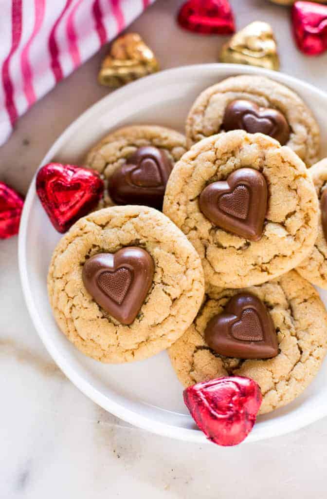 Peanut Butter Cookies with a reese's chocolate heart in the center, stacked on a plate.
