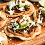 This homemade tostada recipe has seasoned ground beef, creamy refried beans, and all of your favorite toppings on a crispy shell!