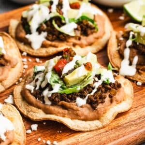 This homemade tostada recipe has seasoned ground beef, creamy refried beans, and all of your favorite toppings on a crispy shell!