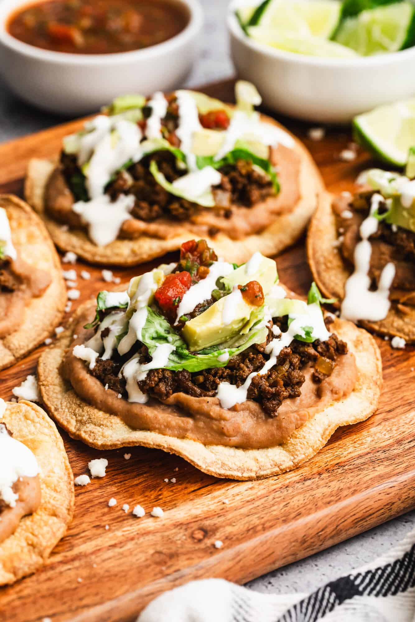 This homemade tostada recipe has seasoned ground beef, creamy refried beans, and all of your favorite toppings on a crispy shell!