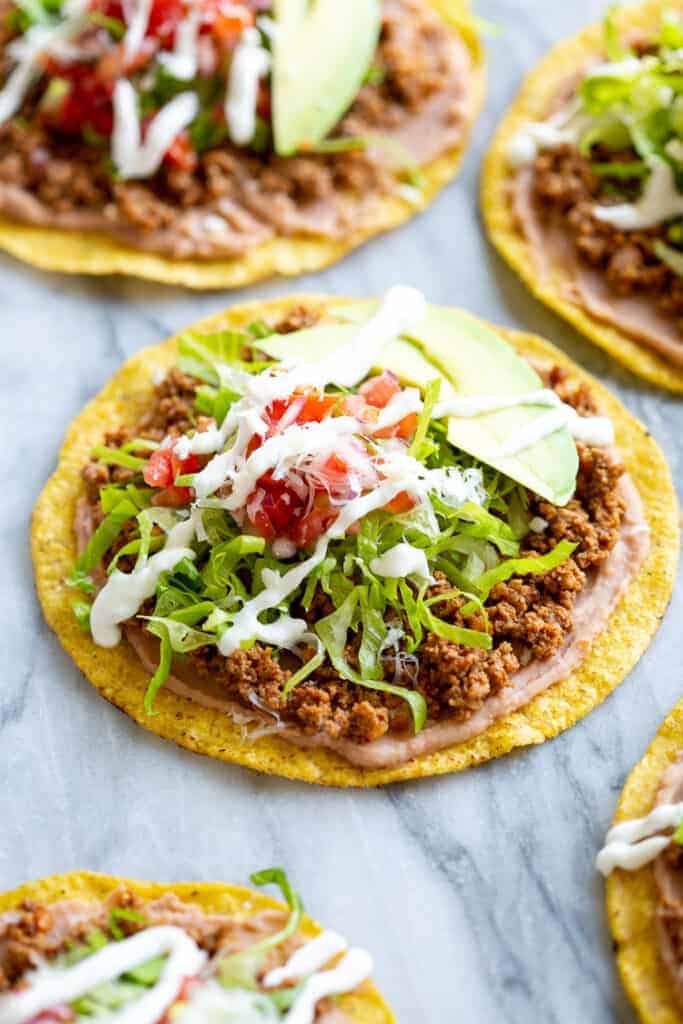 Tostada shells topped with refried beans, seasoned ground beef, lettuce, avocado, pico de gallo and sour cream.