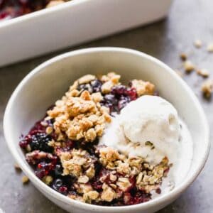 A bowl of berry crisp with a scoop of vanilla ice cream on top.