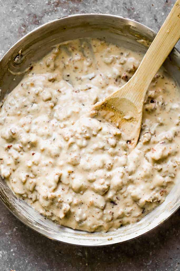 A pan full of sausage gravy, with a wooden spoon for serving.