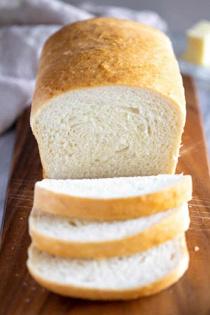 A loaf of homemade bread with three slices cut from it.