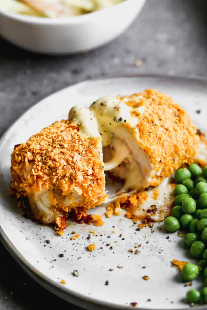 Easy Chicken Cordon Bleu served on a plate with peas, sliced in half to show the melted cheese inside.
