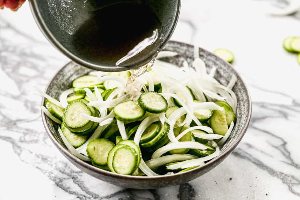 Vinegar dressing poured over chopped cucumber and onion to make a salad.