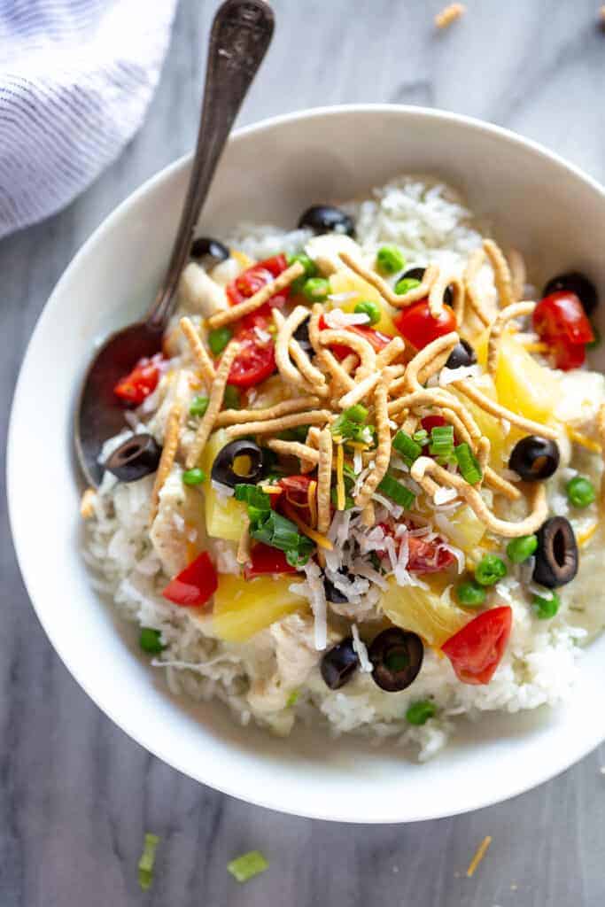 Hawaiian haystacks served over white rice, in a bowl with a spoon.