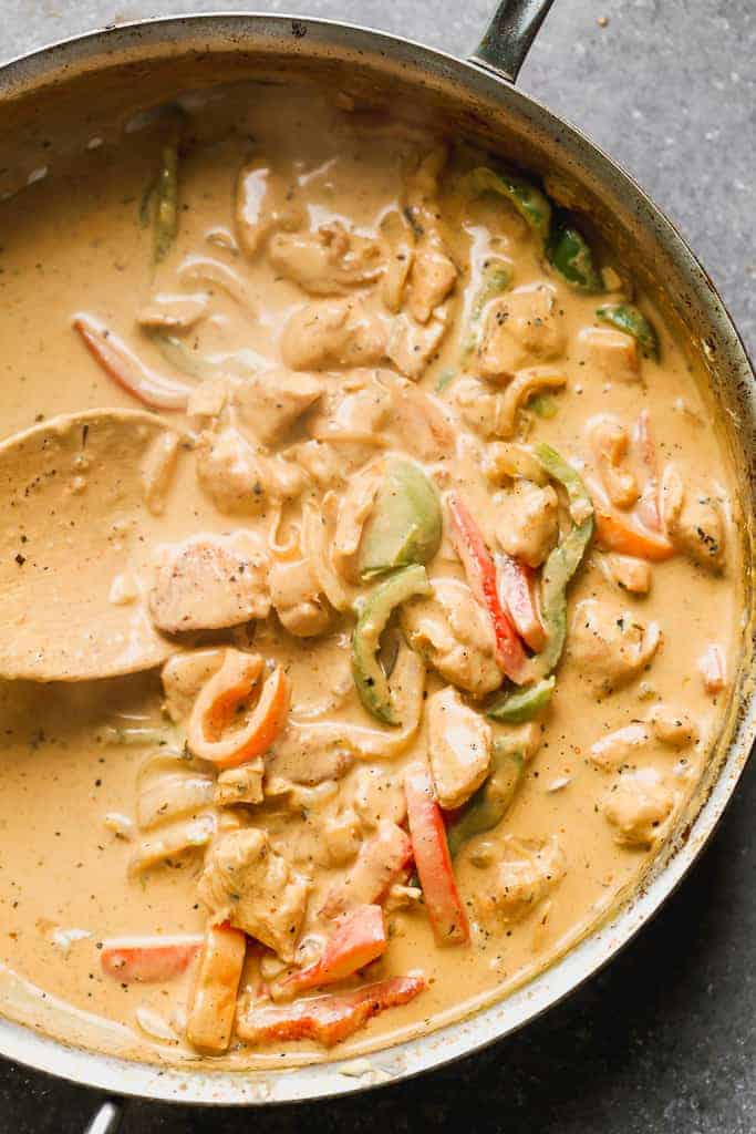 Creamy cajun sauce with chicken and veggies in a skillet.