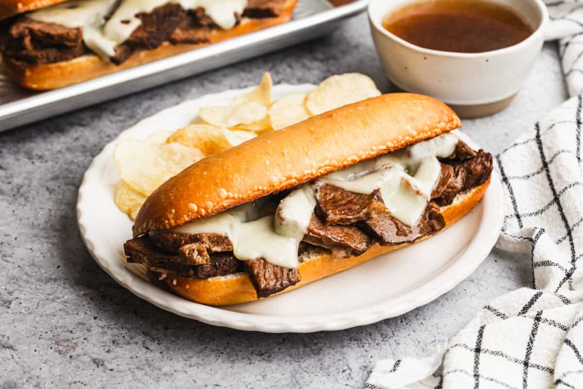 This easy Slow Cooker French Dip Sandwich recipe is loaded with tender sliced meat and broiled with butter and cheese until golden. The au jus is flavorful and delicious!