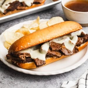 This easy Slow Cooker French Dip Sandwich recipe is loaded with tender sliced meat and broiled with butter and cheese until golden. The au jus is flavorful and delicious!