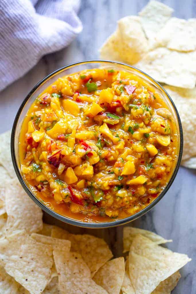 Mango Salsa served in a bowl surrounded by tortilla chips.