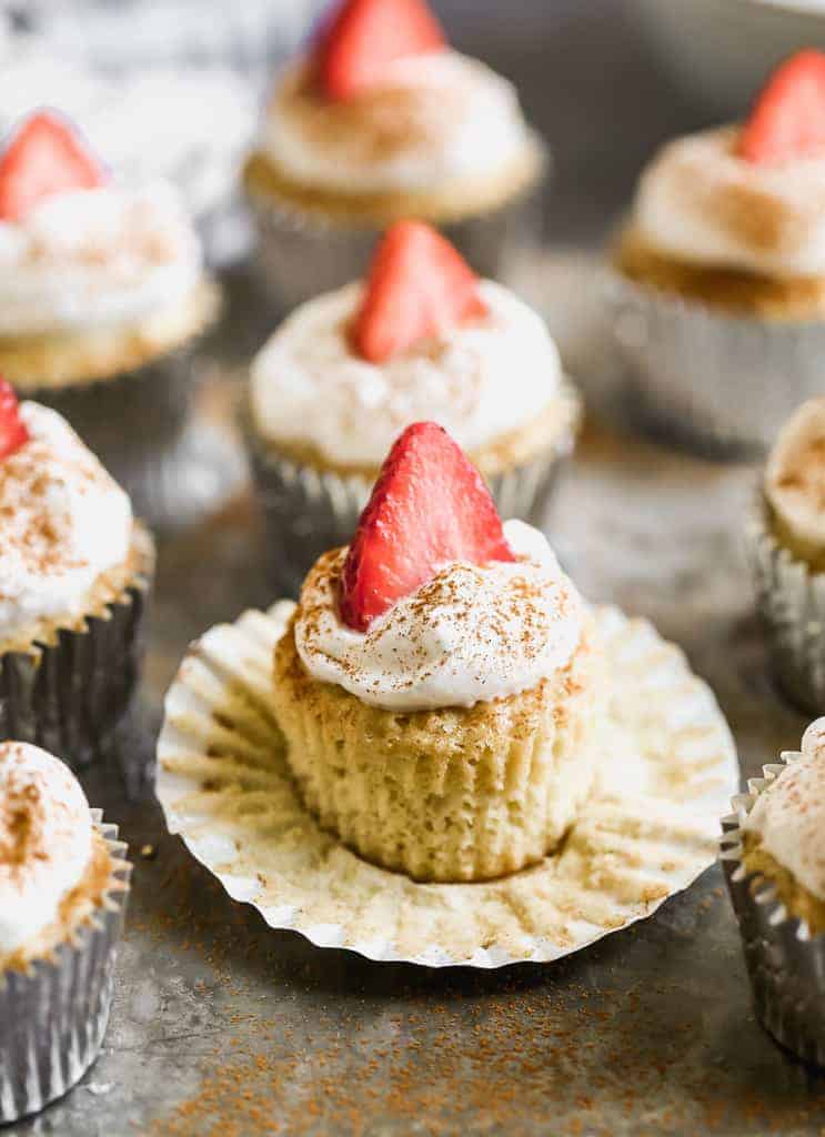 Tres Leches Cupcakes with whipped cream and a strawberry on top.