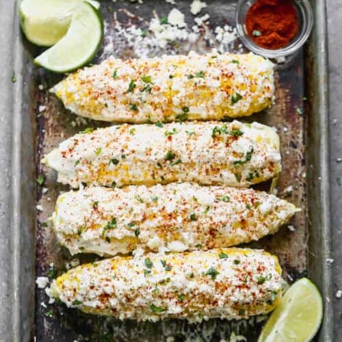 A sheet pan with for elote Mexican street corn cobs on it.