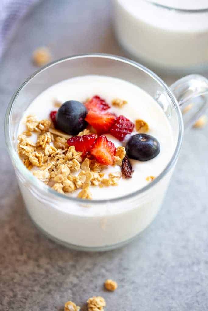 Instant pot yogurt served in a cup with berries and granola on top.