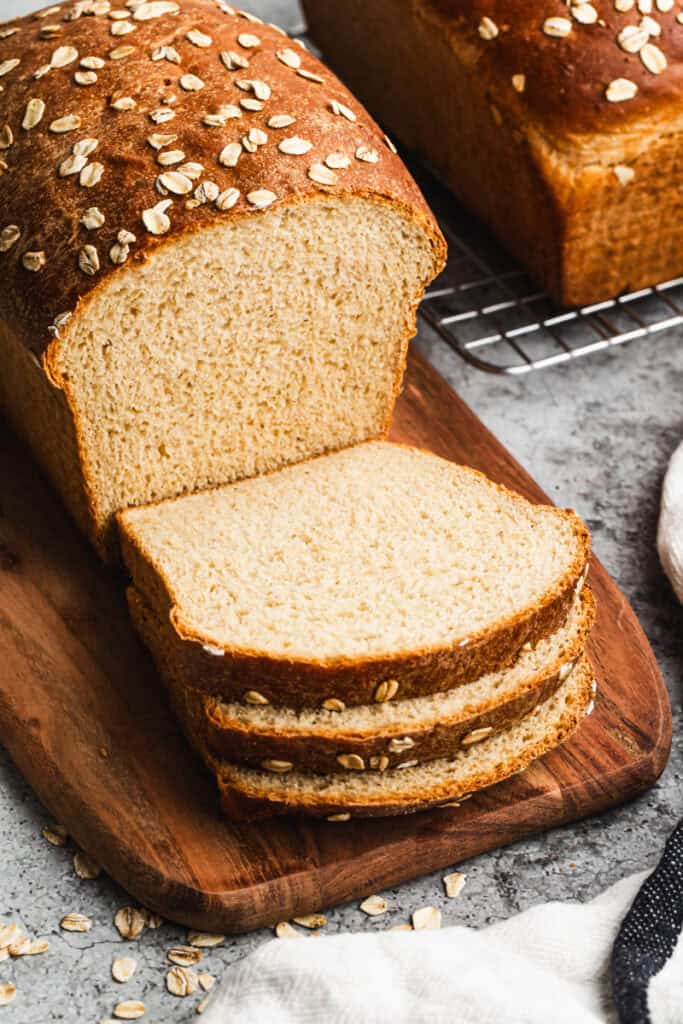 A loaf of homemade Oatmeal Bread with a few slices cut and ready to eat.