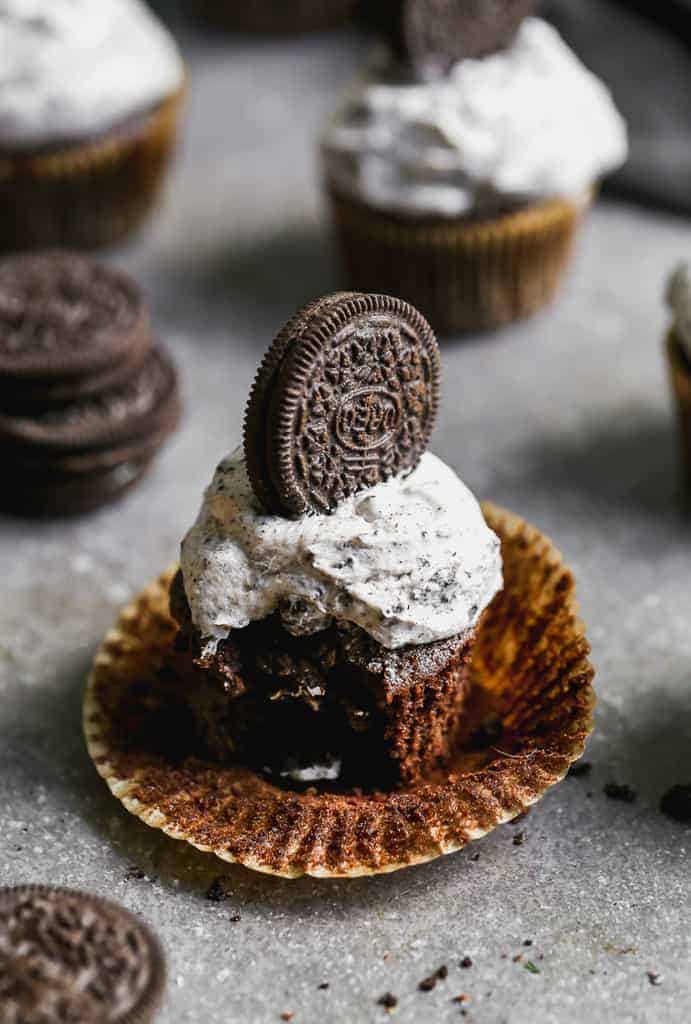 A frosted Oreo cupcake with a bite taken out of it.
