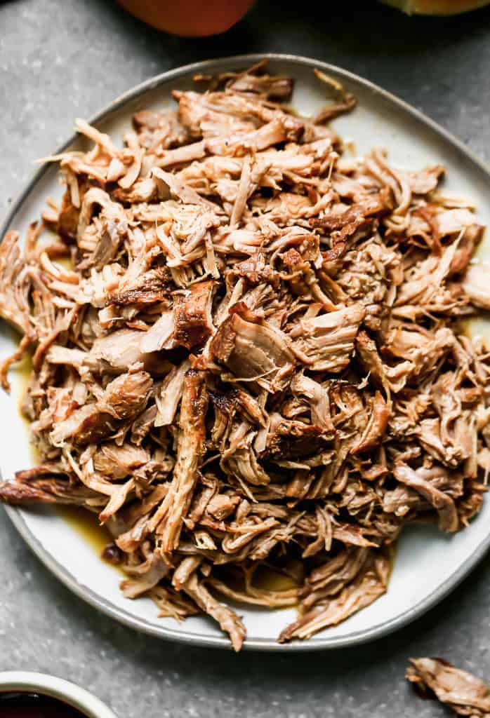 A pile of pulled pork on a white plate.
