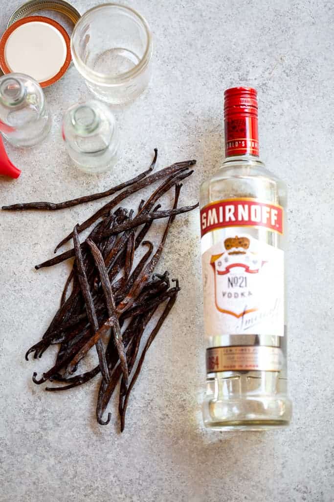 A bottle of vodka, Vanilla beans and jars for making vanilla extract.
