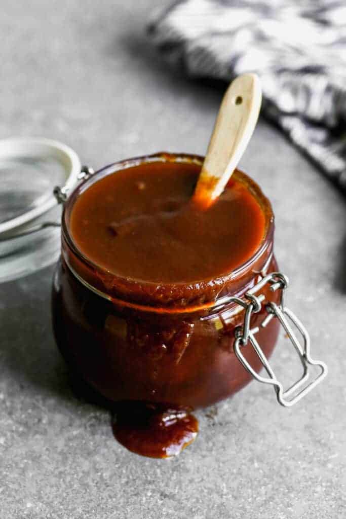 BBQ sauce in a glass jar with a basting brush in it.