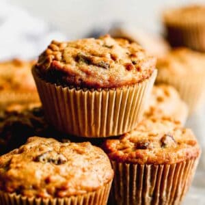 Bran muffins baked in muffin liners, stacked on a board.