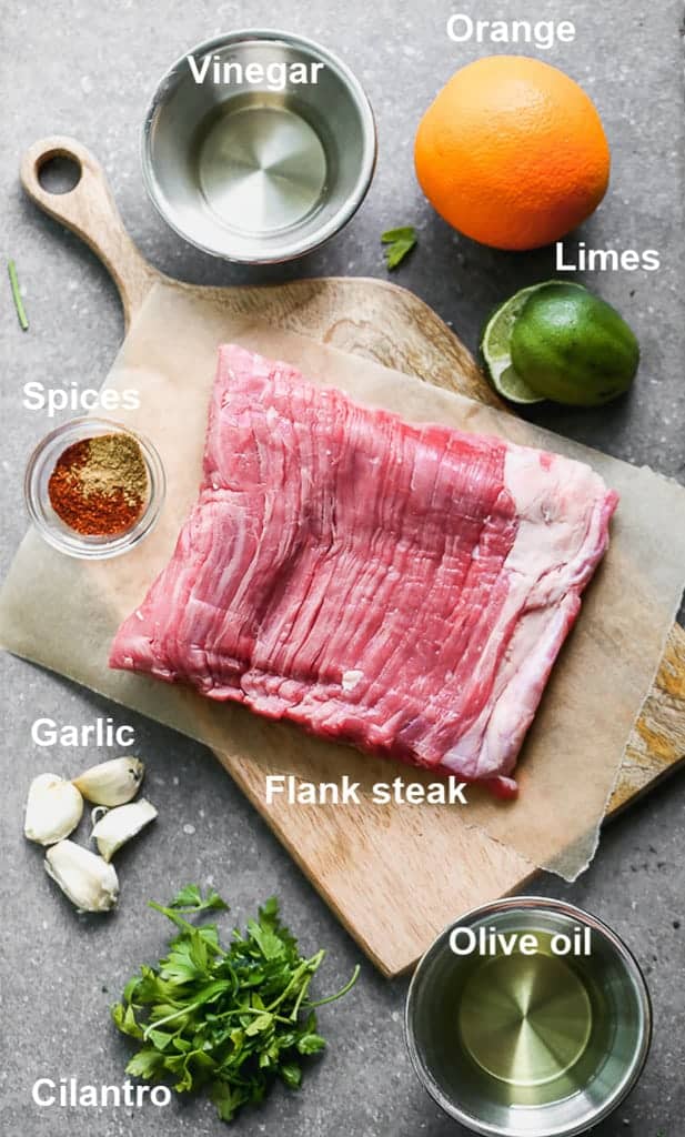 The ingredients needed to make carne asada, labeled, on a wooden board. 