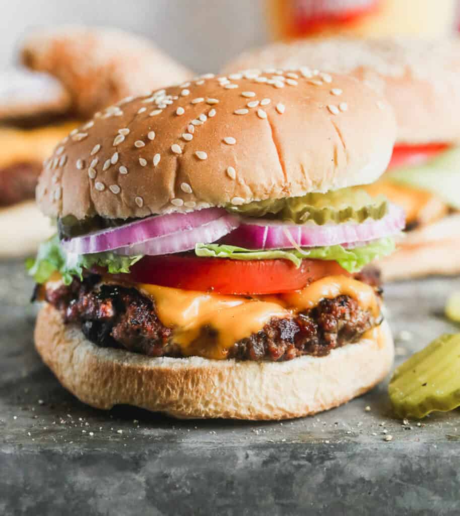 A juicy hamburger recipe with cheese, lettuce, tomatoes, pickles, and red onions ready to enjoy.