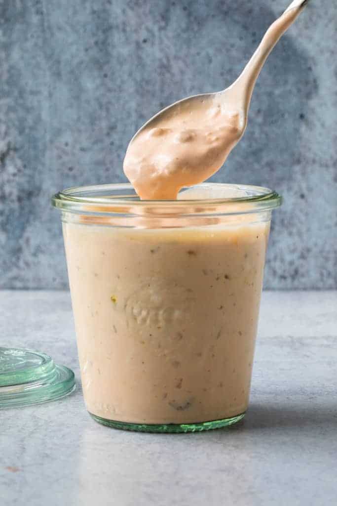 A cup with homemade Thousand Island Dressing with a spoon lifting some out.