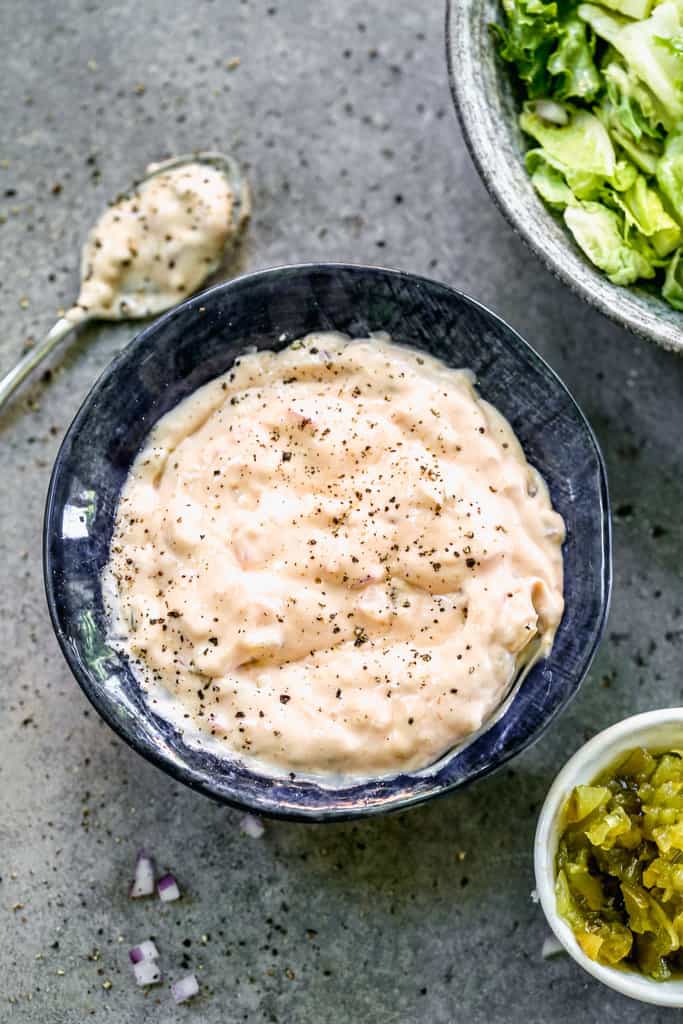 A bowl of homemade Thousand Island Dressing with a spoon next to it.
