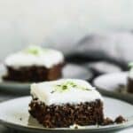 A zucchini brownie with cream cheese frosting, on a plate.