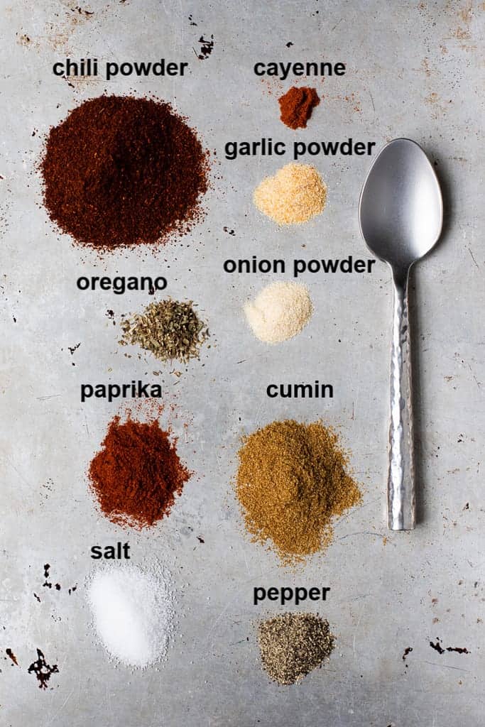 The ingredients needed to make taco seasoning measured onto a board and labeled.