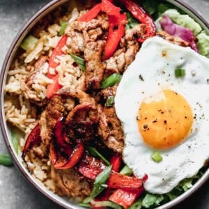 This flavorful Bulgogi Bowls is bold and delicious with a bed of kimchi fried rice, tender marinated pork, peppers, and an egg on top.