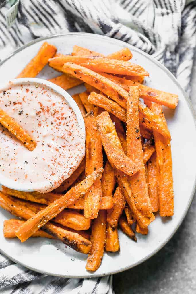 Sweet potato fries on a white plate with a side of fry sauce.
