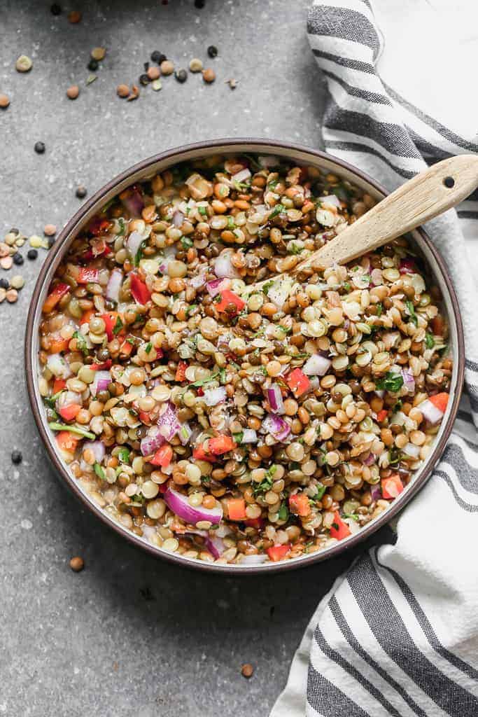Lentil Salad in a serving bowl with a wooden spoon.