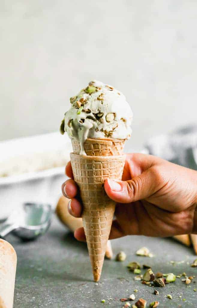 A waffle cone with a scoop of homemade pistachio ice cream in it.