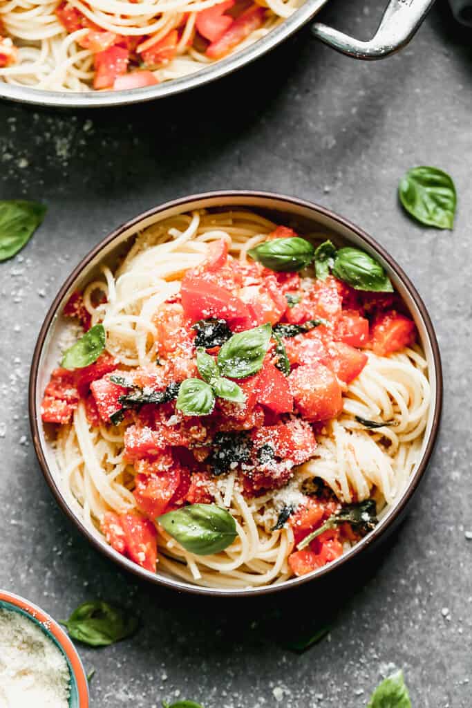 Pâtes à la tomate et au basilic avec tomates fraîches et basilic sur nouilles spaghetti, servies dans un bol.