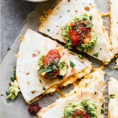 Breakfast quesadilla cut into triangles, topped with sour cream, salsa and guacamole.