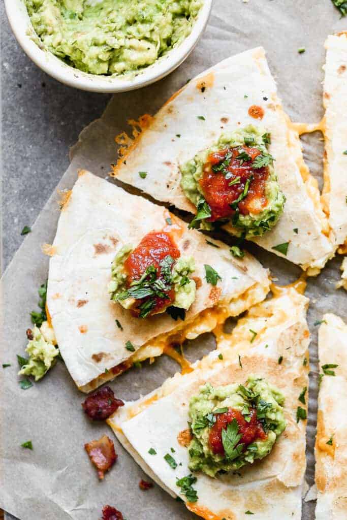 Breakfast quesadilla cut into triangles, topped with sour cream, salsa and guacamole.