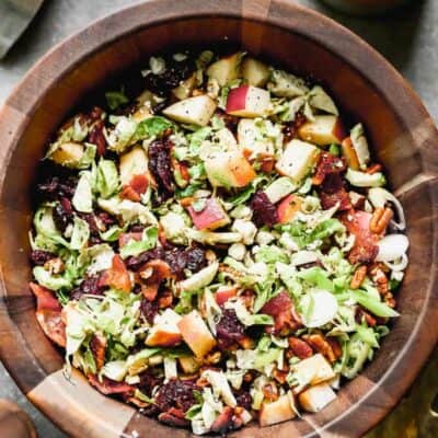 Brussels sprout salad with apples and bacon, served in a wooden serving bowl.