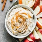 Caramel apple dip in a bowl with sliced apples on the side.