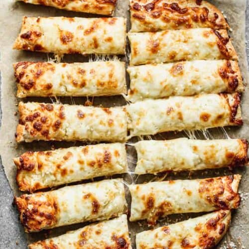 Cheesy breadsticks cut into pieces, with marinara sauce in a bowl on the side.