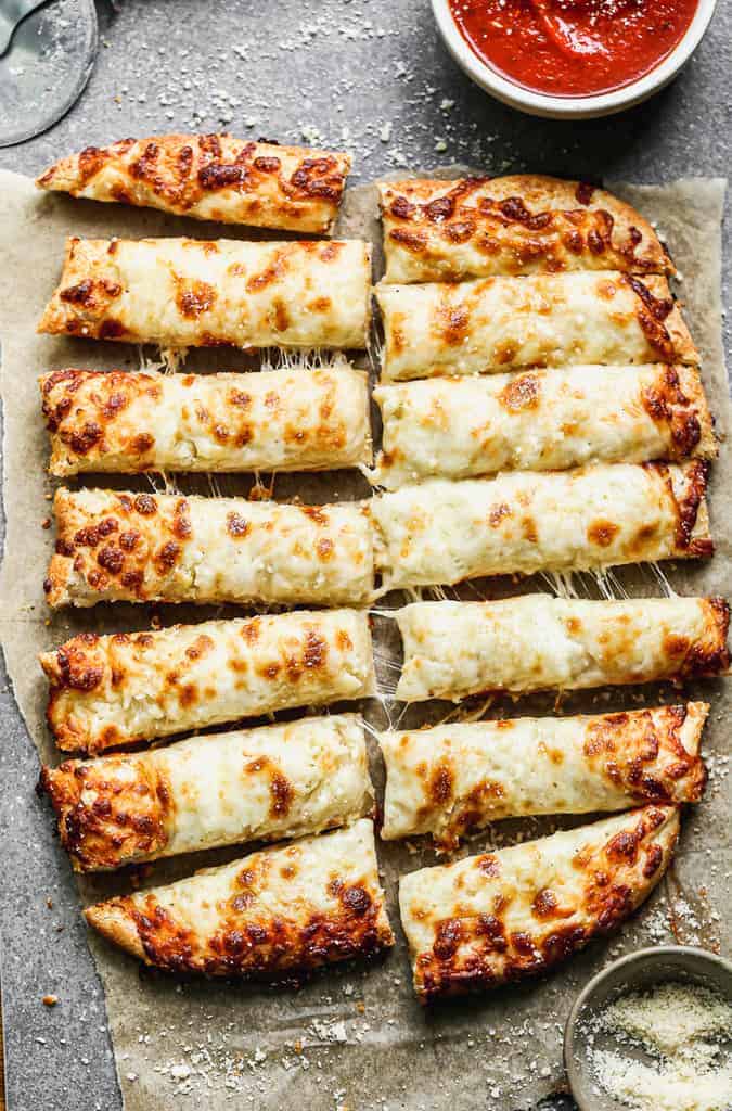 Cheesy breadsticks cut into pieces, with marinara sauce in a bowl on the side.