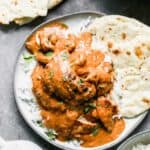 A plate of chicken tikka masala served over rice, with a side of naan.