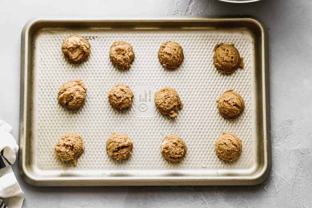 Gingersnap cookie dough balls on a baking sheet.