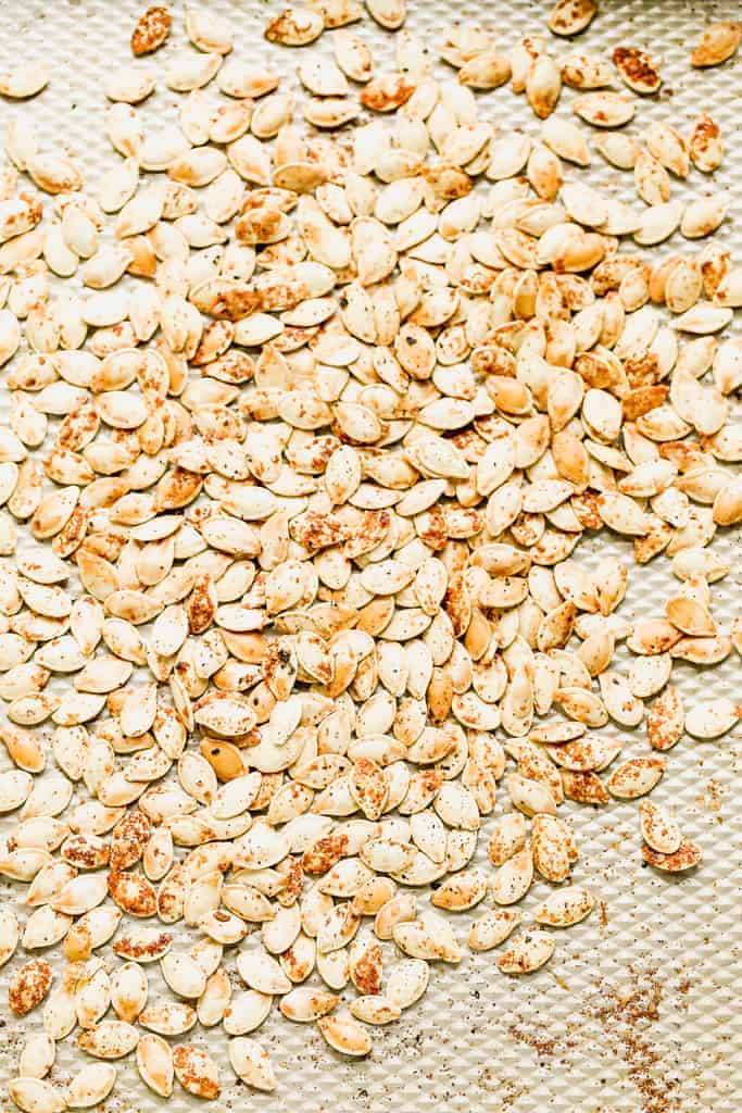 Seasoned, roasted pumpkin seeds on a baking sheet.