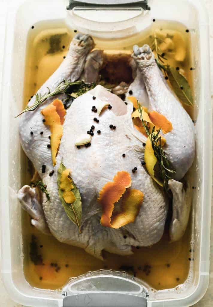 A full uncooked turkey in a large plastic container with brine.